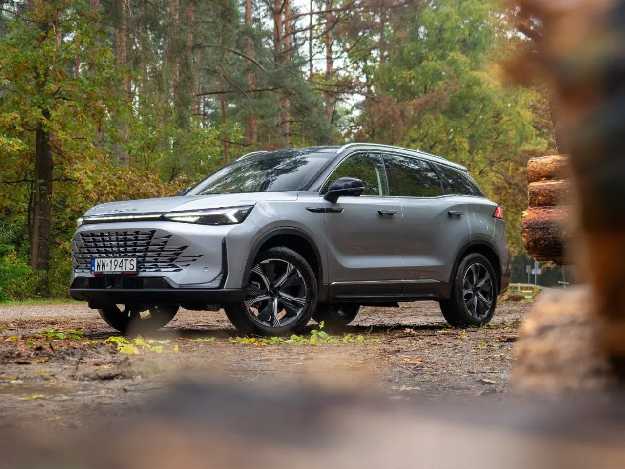 Srebrny SUV w lesie, gotowy na przygodę. Wiele pozytywnych baic 7 opinii potwierdza jego wszechstronność.