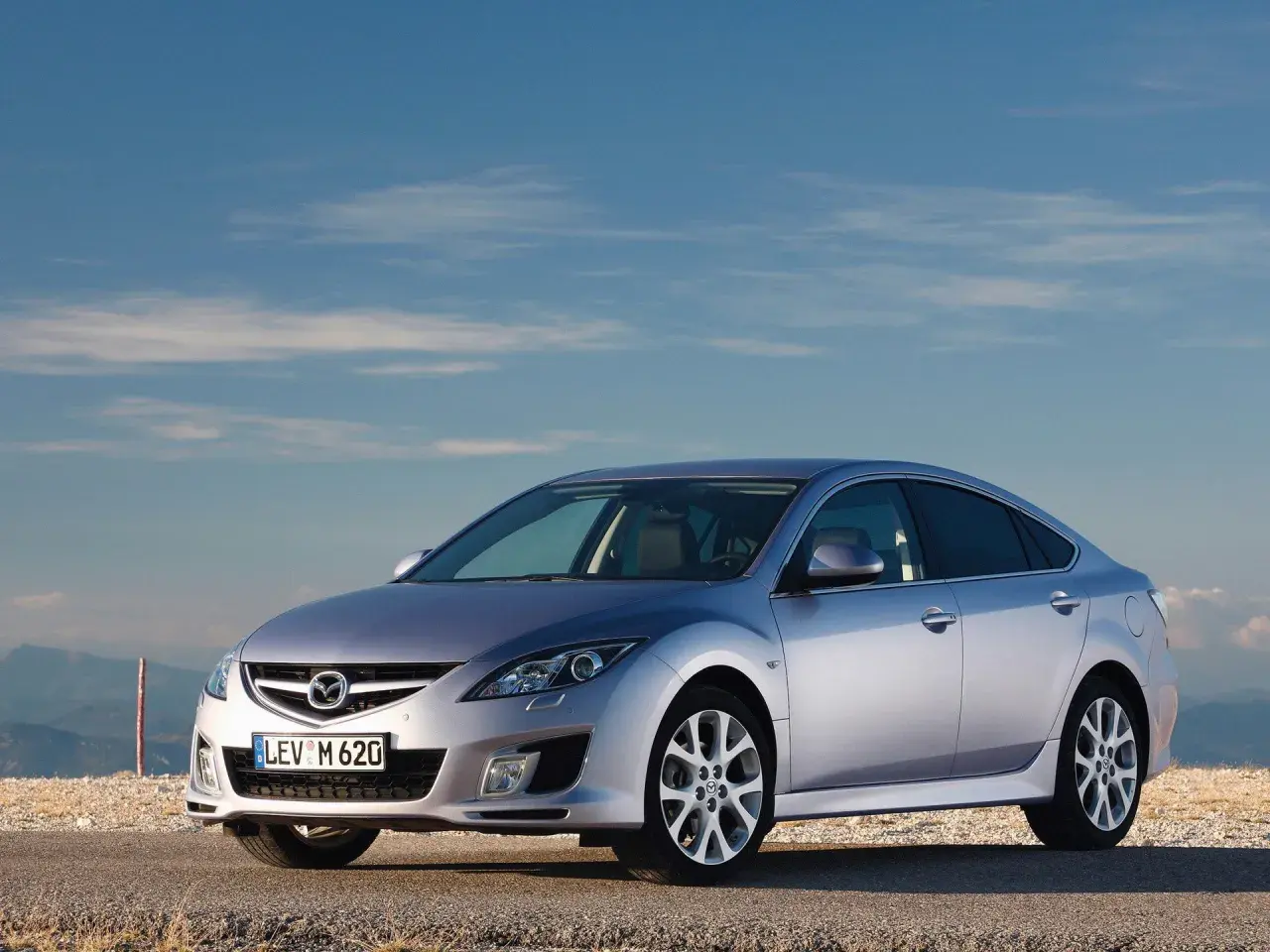 Srebrna Mazda 6 2.0 benzyna na tle błękitnego nieba i gór.