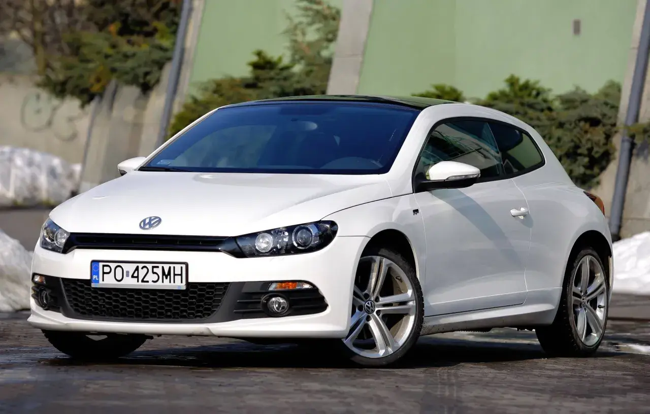 Biały Volkswagen Scirocco z czarnym dachem, zaparkowany na zewnątrz.