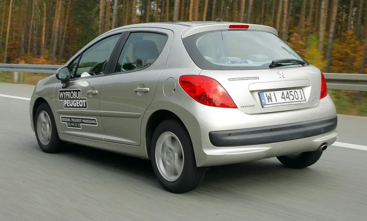 Srebrny Peugeot 207 1.4 benzyna w ruchu drogowym. Na drzwiach naklejka "Wypróbuj Peugeot".