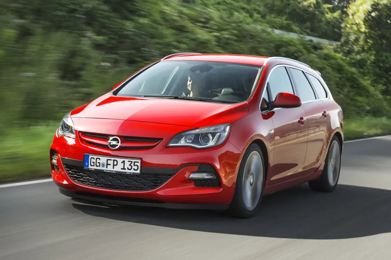 Czerwony Opel Astra J 1.4 Turbo 140 KM na drodze. Kierowca zadowolony, auto w ruchu.