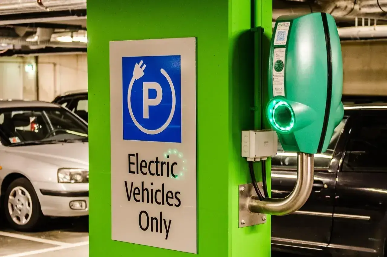 Zielona ładowarka EVbox i znak "Electric Vehicles Only" w garażu podziemnym. Zastanawiasz się, ile kosztuje ładowanie samochodu elektrycznego?