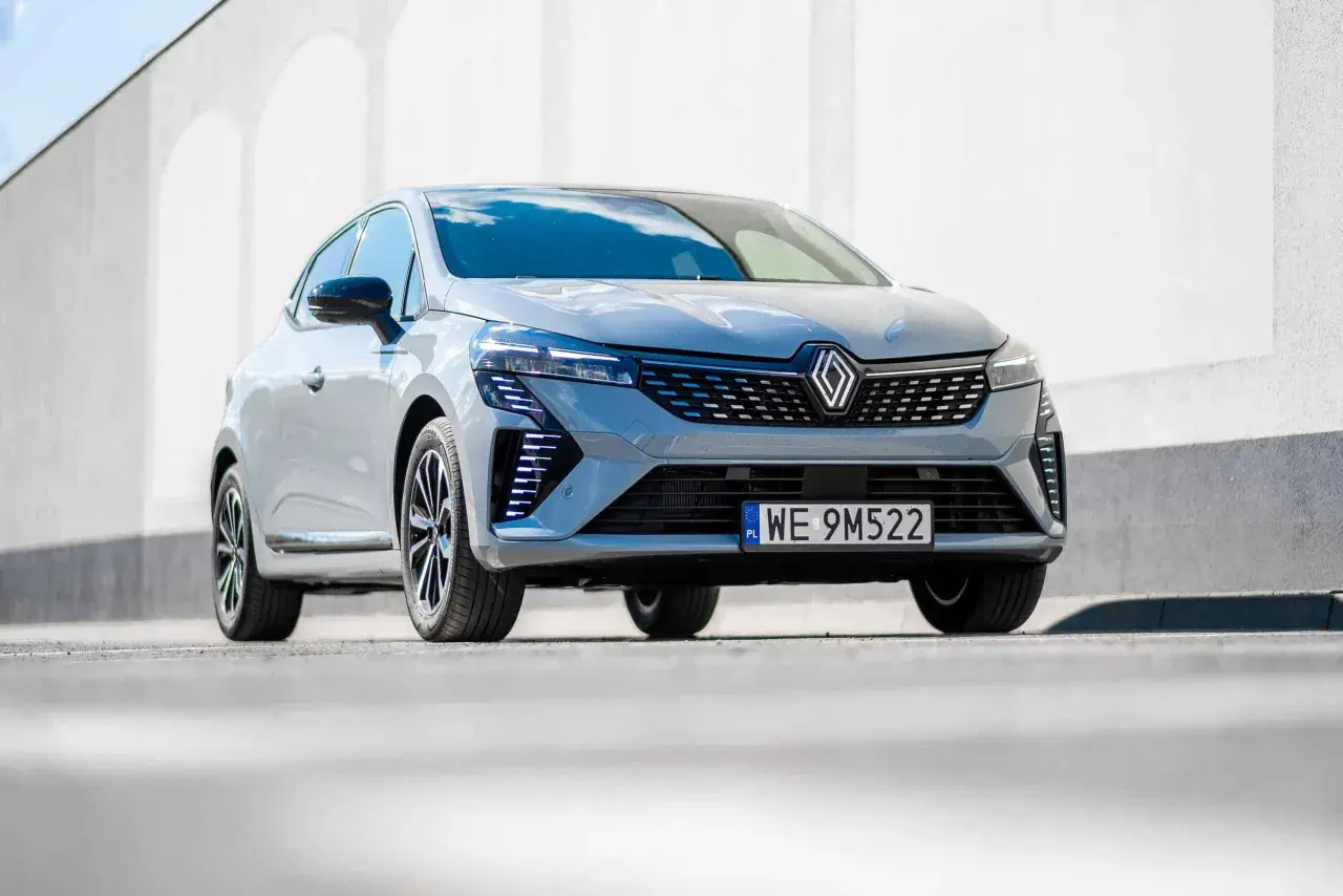 Nowoczesne Renault Clio 2024 w szarym kolorze prezentuje się dynamicznie na tle białej ściany.