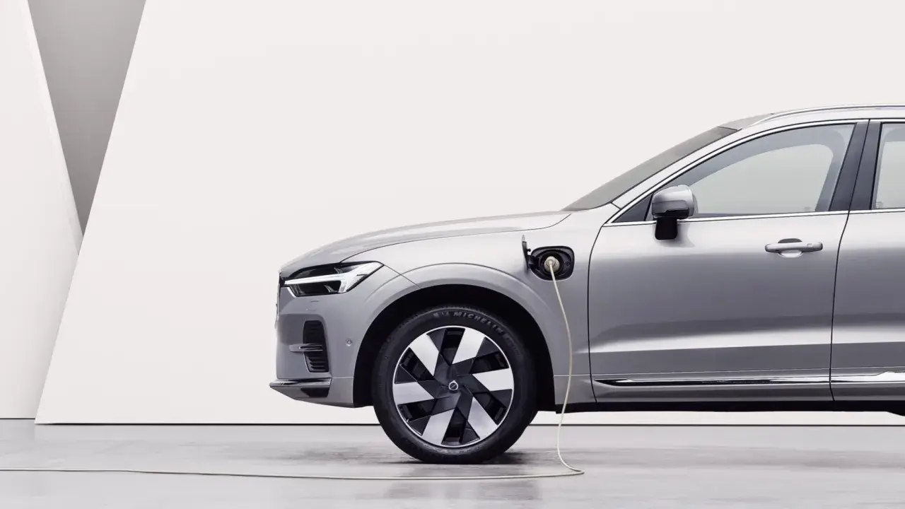 Srebrny samochód typu PHEV jest ładowany. To połączenie silnika spalinowego i elektrycznego, co oznacza, że możesz jeździć na prądzie lub paliwie.