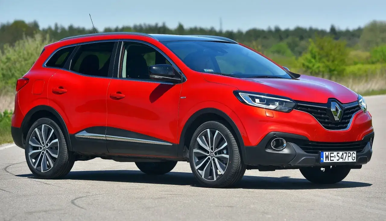 Czerwony Renault Kadjar na drodze. Wiele pozytywnych **renault kadjar opinie** potwierdza jego atrakcyjny wygląd i komfort jazdy.