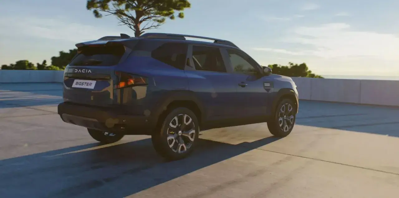Niebieski Dacia Bigster na tle nieba i drzewa. Zbliżają się jego wymiary.