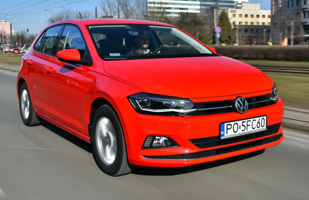 Czerwony Volkswagen Polo 6 w ruchu miejskim. Kierowca w szarej bluzie prowadzi auto.