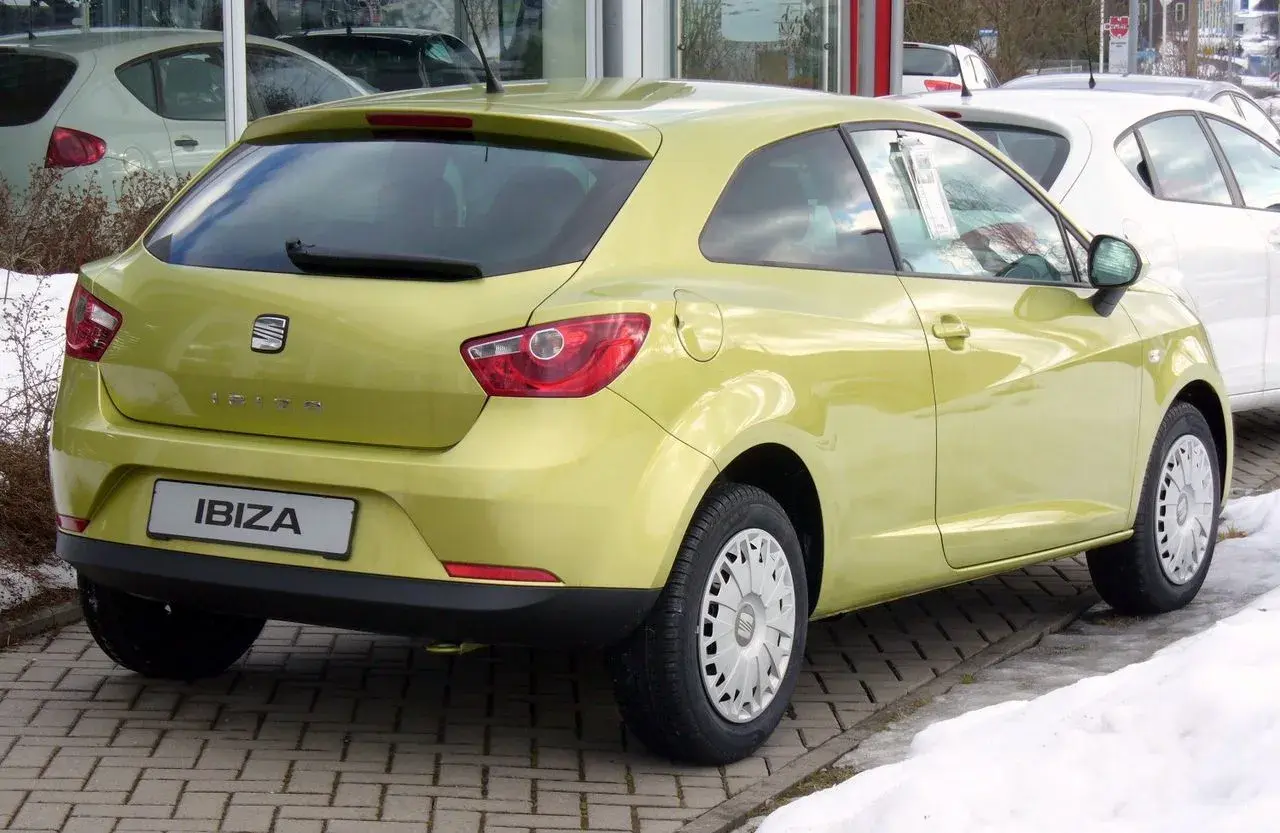 Żółty Seat Ibiza 1.4 benzyna z tyłu, zaparkowany na kostce brukowej.