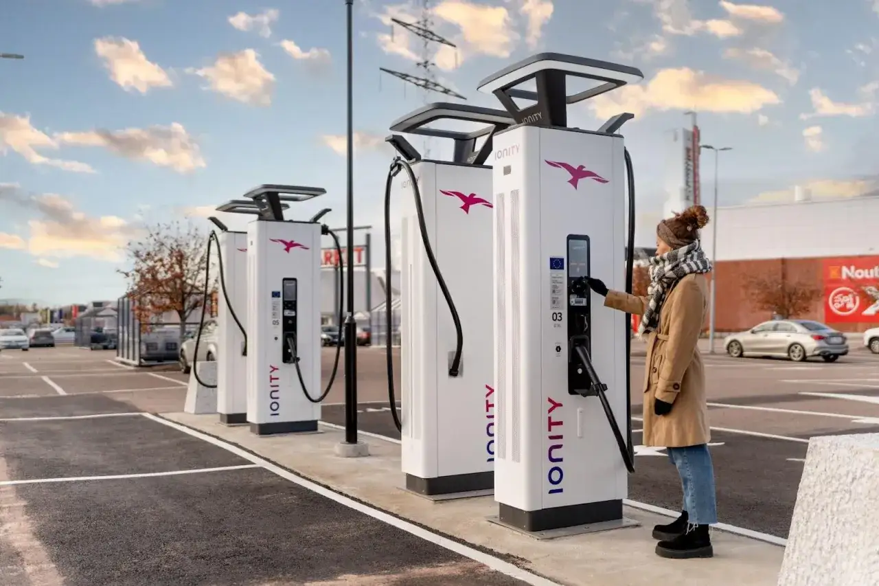 Kobieta ładuje auto elektryczne na stacji Ionity. DC to prąd stały, kluczowy dla szybkiego ładowania.