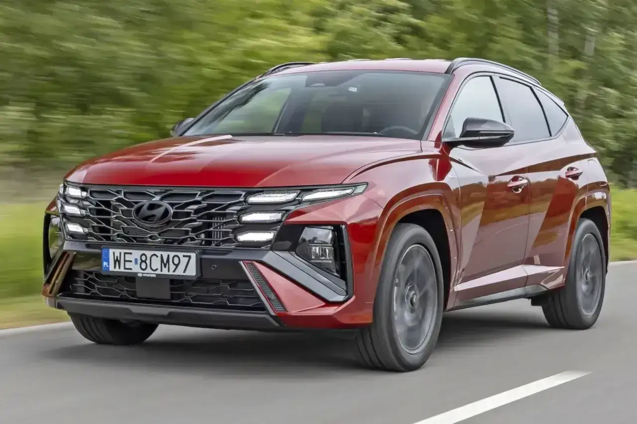 Czerwony Hyundai Tucson w ruchu drogowym. Zwróć uwagę na jego nowoczesny design i imponujące hyundai tucson wymiary, które zapewniają komfort i przestronność.