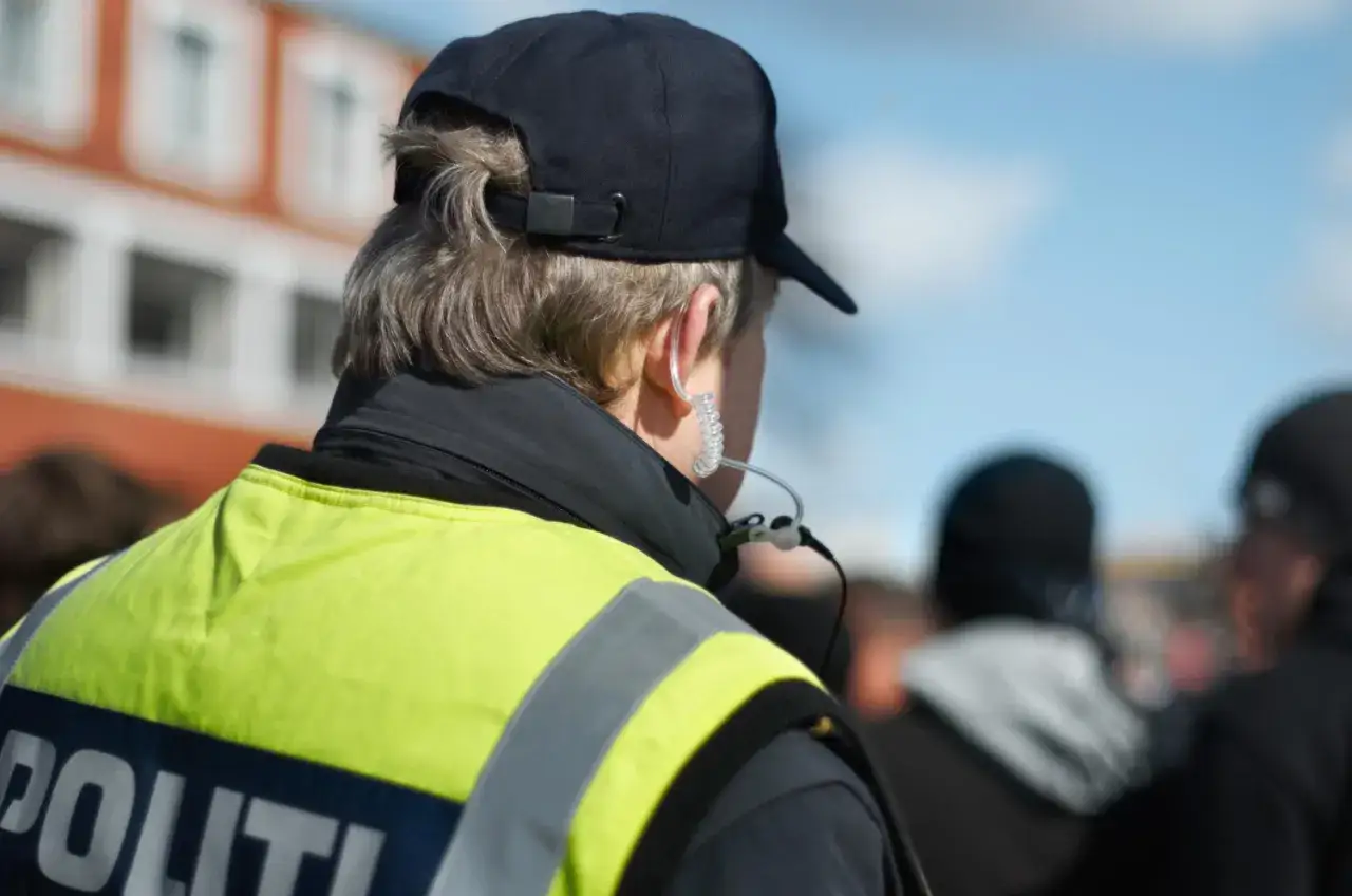 Policjant w kamizelce odblaskowej i czapce, z zestawem słuchawkowym w uchu. Czy sprawdzi, ile promili ma kierowca?