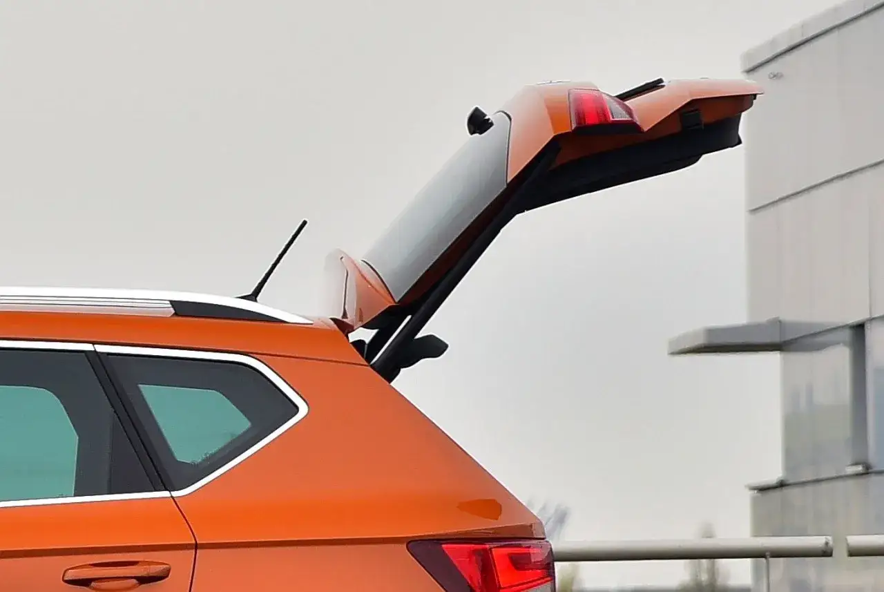 Pomarańczowy Seat Ateca z otwartym bagażnikiem. Wiele osób szuka seat ateca opinie, by sprawdzić jego funkcjonalność.
