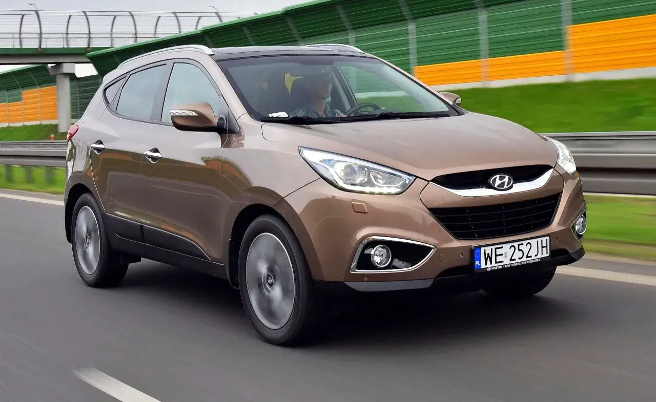 Brązowy Hyundai ix35 na drodze. Wiele pozytywnych hyundai ix35 opinie potwierdza jego komfort i niezawodność.