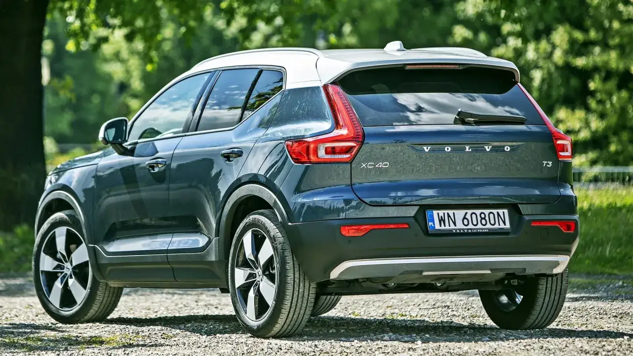 Tylna część ciemnoszarego Volvo XC40 z białym dachem, zaparkowanego na żwirowej drodze. Sprawdź aktualną volvo xc40 cena.